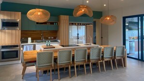 A modern kitchen with a central island, wooden cabinets, and hanging pendant lights. - Casa Palmeras • Luxury Villa Near Beach & Surf (Tamarindo)