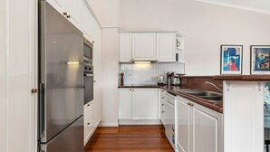 Une cuisine moderne avec des meubles blancs, des appareils en acier inoxydable et un plancher en bois.