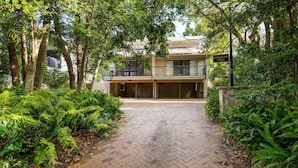 Un bâtiment sur lequel on peut lire l’inscription « Kookaburra Lodge », entouré d’une végétation luxuriante et doté d’une entrée dallée.