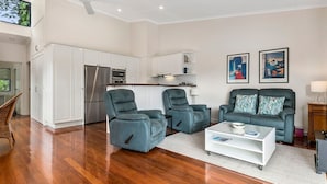 Un grand espace de vie comprenant une cuisine, deux fauteuils, un canapé et une table basse.