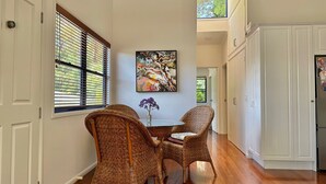 Un coin repas avec des chaises en osier, une table et un tableau accroché au mur.