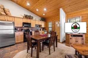Une cuisine aménagée dans le style d’un chalet en bois, avec une table et des chaises en bois, un réfrigérateur, un four à micro-ondes et des placards.