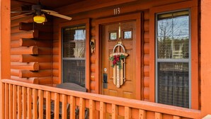 A wooden cabin with a porch, a number 113 sign, and a Christmas wreath. - Romantic Studio Cabin for Two with Private Balcony, Jetted Tub, and Gas Fireplace (Branson)