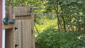A wooden gate leading to a backyard with a wooden shed, surrounded by greenery and a garden path. - Tranquil 3 bedroom waterfront cottage on private lake! (Rideau Lakes)