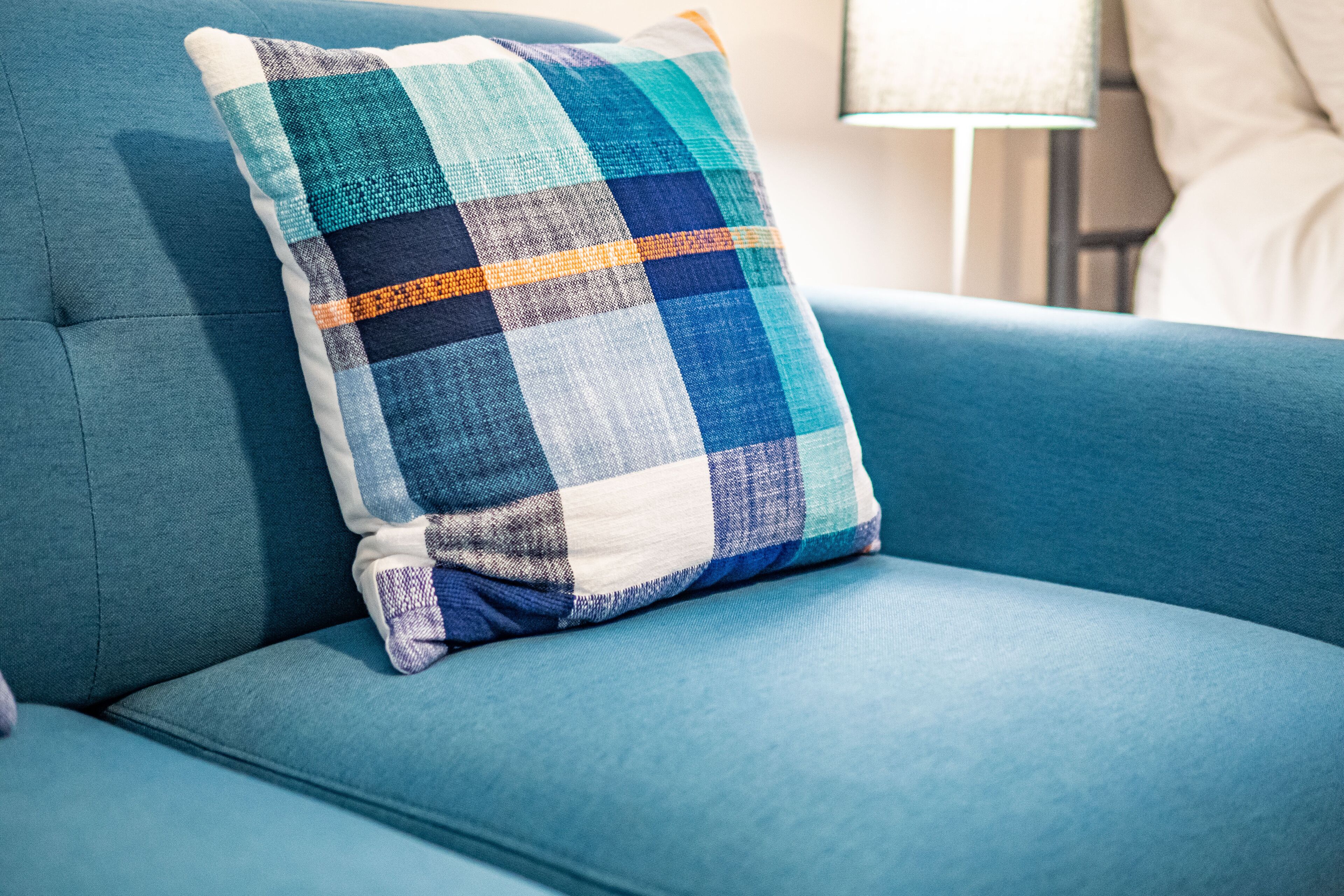 A blue sofa with a checkered pillow.