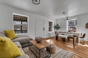 A modern living room with a sofa, coffee table, and dining area.