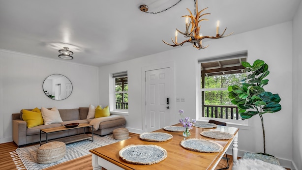 A dining area with a wooden table, woven placemats, and a chandelier.