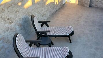 Terraza en la azotea con dos sillones y una mesa, con vistas a un paisaje urbano y montañas.