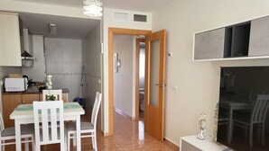 A modern kitchen with white cabinets, a microwave, and a dining area with a white table and chairs. - Front line duplex penthouse with private pool! (Vera)