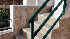 A staircase with stone walls and green metal railings. - Front line duplex penthouse with private pool! (Vera)