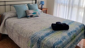 A bedroom with a bed, a ceiling fan, a painting, a nightstand, and a window with curtains. - Front line duplex penthouse with private pool! (Vera)