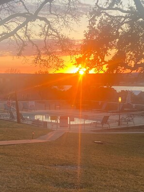 Solnedgang over en park med pool og liggestole.