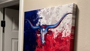 Een schilderij van een blauw en rood stierenhoofd met een witte ster op een beige muur.