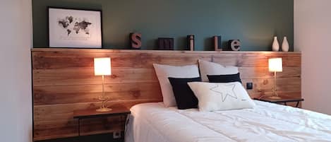 Un dormitorio con cabecera de madera, un mapa mundial enmarcado y la palabra 'SMILE' en la pared. Hay dos mesitas de noche con lámparas.