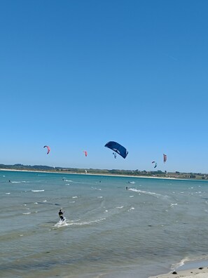 Una playa con cielos despejados y varios cometas volando.