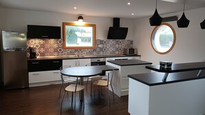 Una cocina moderna con una isla central, un comedor con sillas y un amplio ventanal que proporciona luz natural.