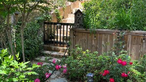 Un sentier de jardin bordé de pierres plates, entouré d’une végétation luxuriante et de plantes en fleurs.