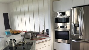 Eine moderne Küche mit weißen Schränken, Edelstahlgeräten und Holzboden.