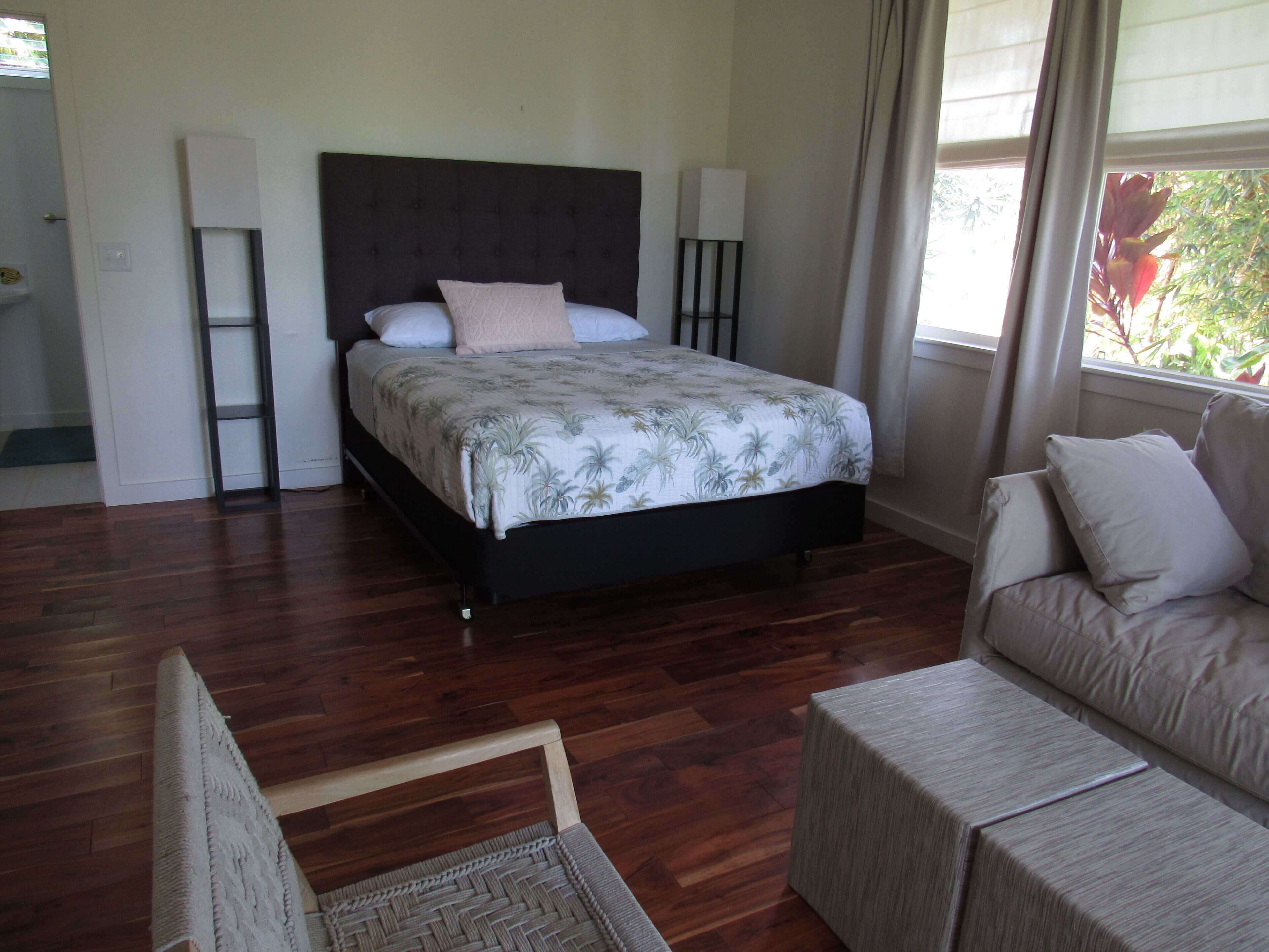 A bedroom with a bed, bedside tables, a sofa, and a window with curtains.