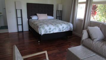 A bedroom with a bed, bedside tables, a sofa, and a window with curtains.