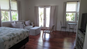 Ein Schlafzimmer mit Bett, einer Couch, einem Sessel, einem kleinen Tisch und einem Fernseher.