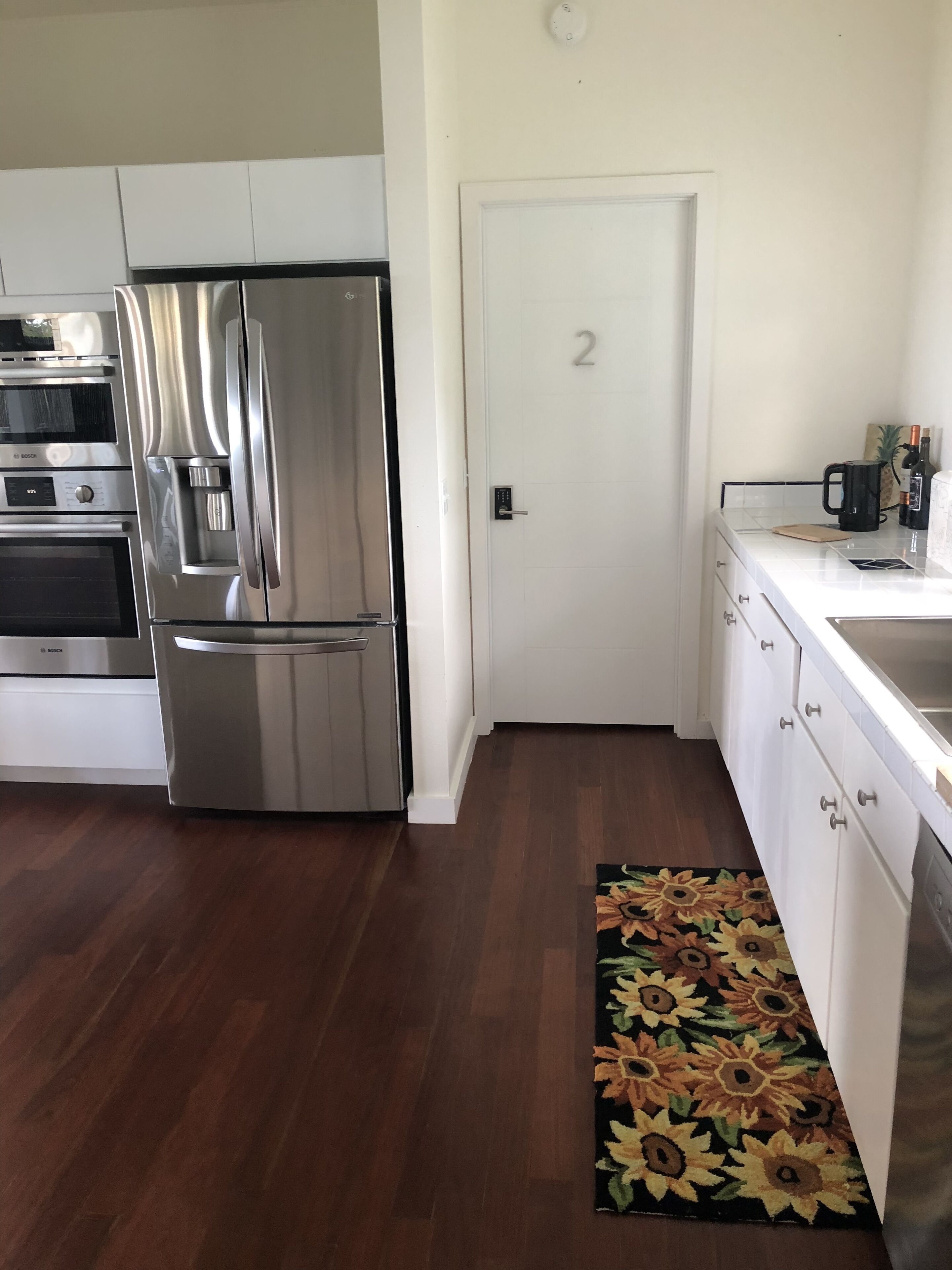 Una cocina moderna con electrodomésticos de acero inoxidable, una puerta blanca y un tapete floral.