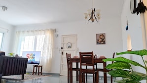 Un comedor con una mesa de madera, sillas y un televisor.