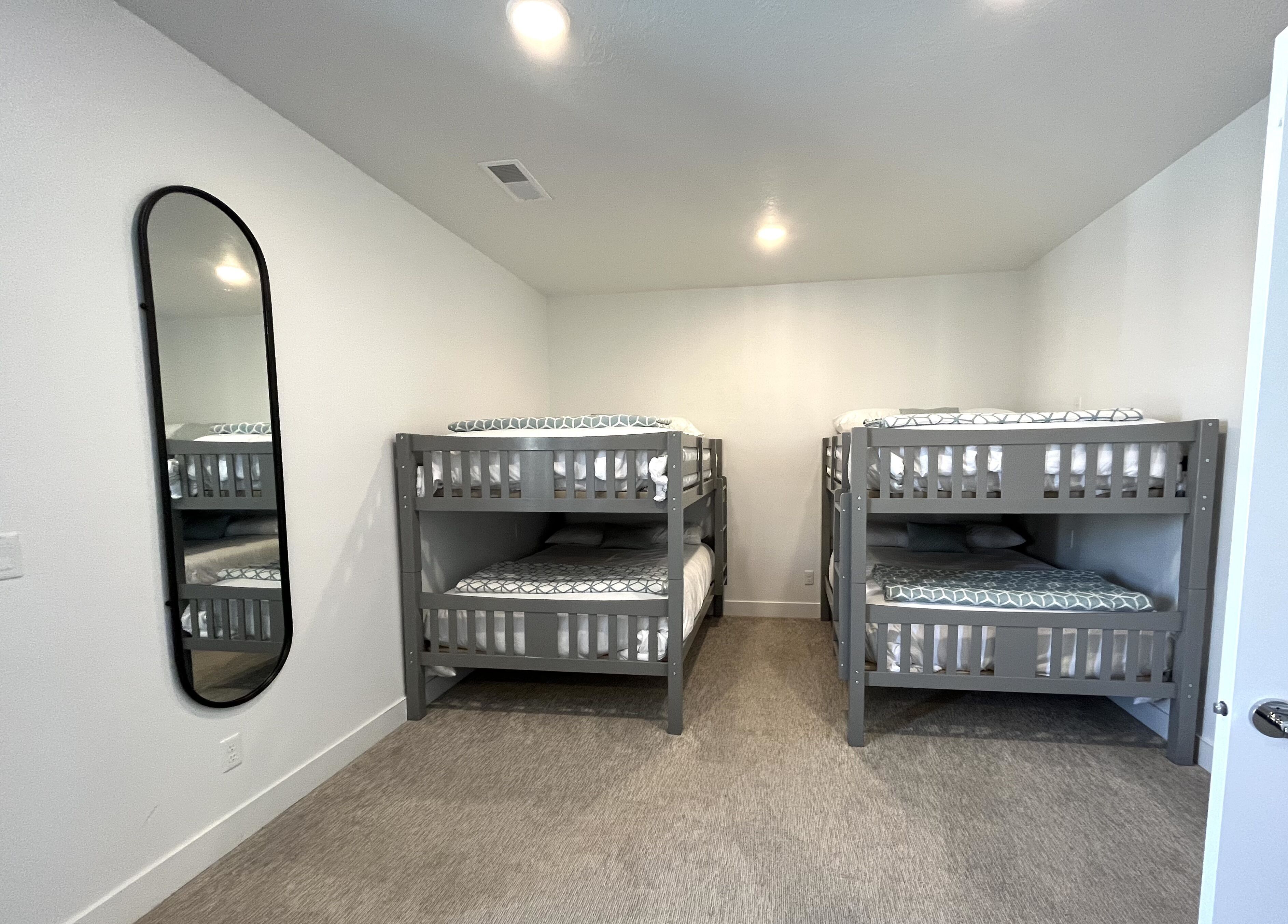 A room with two bunk beds, a large mirror, and a carpeted floor.