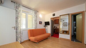 A compact living space with a sofa, a television, a refrigerator, and a kitchen area visible through an open door. - Beautiful apartment in Nin with WiFi (Nin)