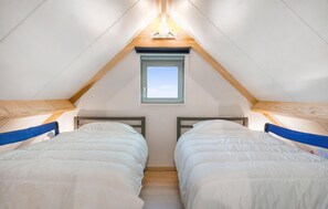 Ein Schlafzimmer mit zwei Betten, einem Oberlicht und Holzbalken.