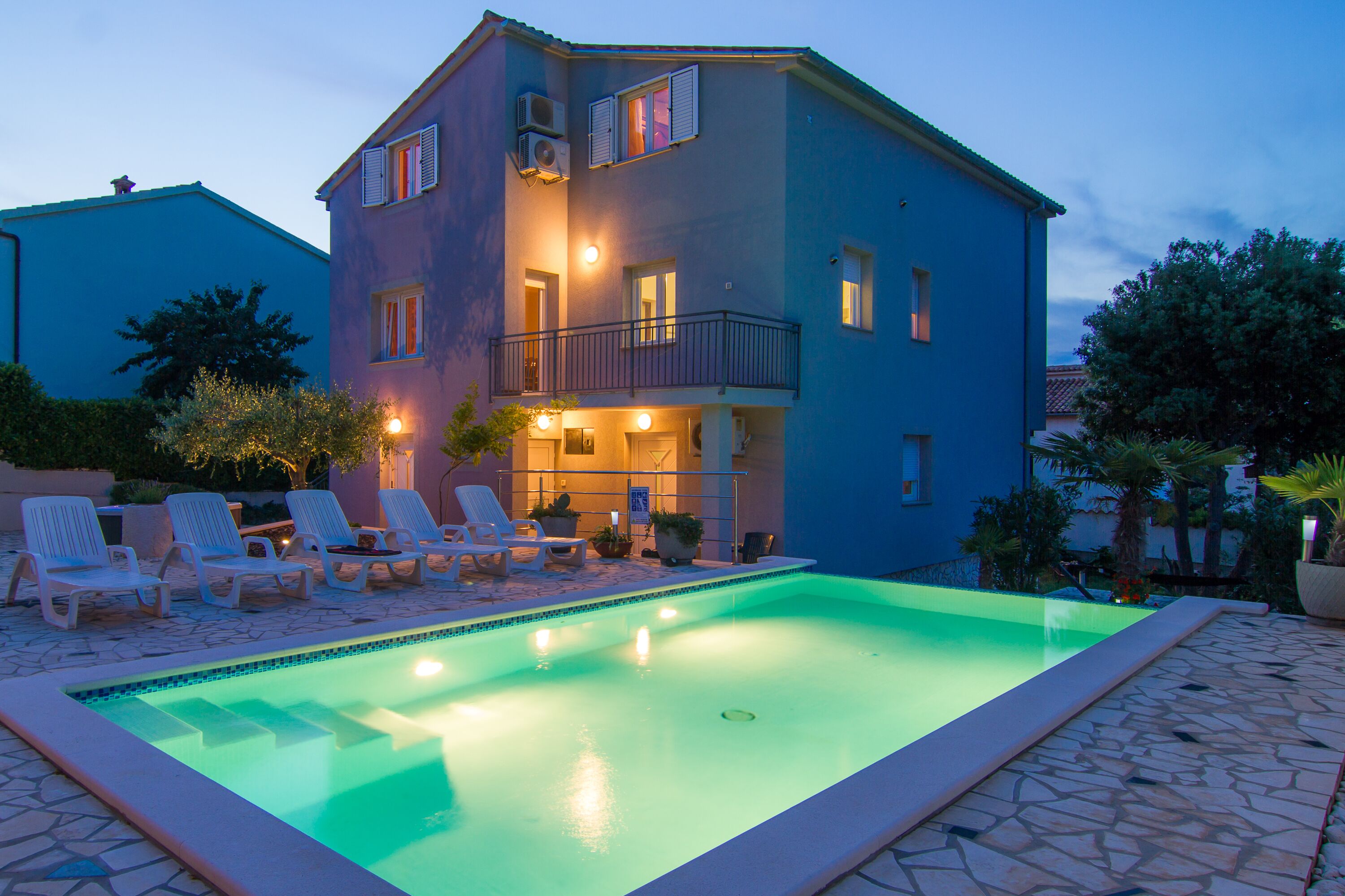 A two-story building with a swimming pool, outdoor seating, and a balcony.