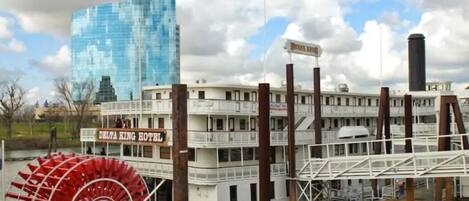 Um hotel em barco de rio com uma grande roda de pás vermelha, fachada branca e um letreiro com a inscrição "DELTA KING HOTEL".