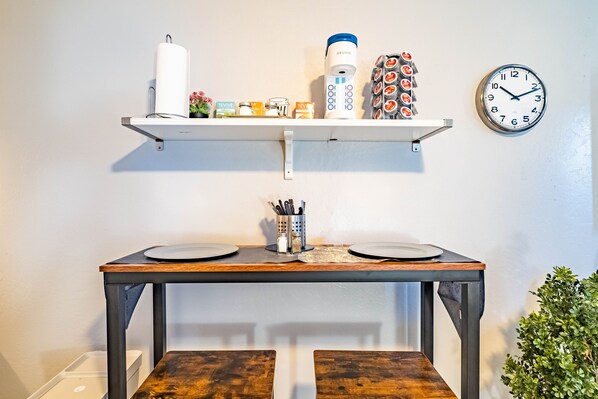 A kitchen with a wooden table, two plates, a coffee maker, and a clock on the wall. - Private Studio in Carmichael w/Netflix, Disney+ (Sacramento)