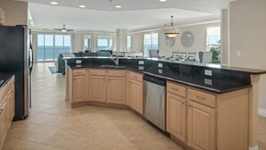 A spacious kitchen with a large island, wooden cabinets, and a view to the outside.