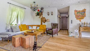 Un salon chaleureux avec un canapé, des fauteuils, une table basse en bois et un chat.