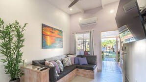 A modern living room with a sectional sofa, a large painting, and a bamboo plant. - Small romantic getaway to remind people why they fell in love (Jaco)