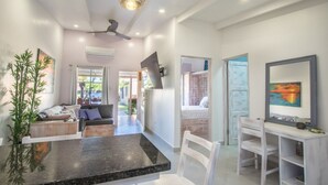 A modern interior with a dining area, a sofa, a TV, and a desk with a chair. - Small romantic getaway to remind people why they fell in love (Jaco)