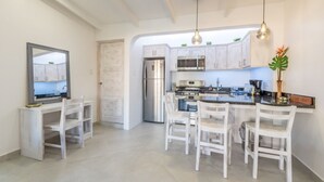 A modern kitchen with white cabinetry, stainless steel appliances, and a central island with seating. - Small romantic getaway to remind people why they fell in love (Jaco)