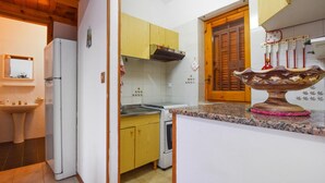 Una cocina compacta con gabinetes de madera, horno empotrado y un adorno cerámico en la encimera.