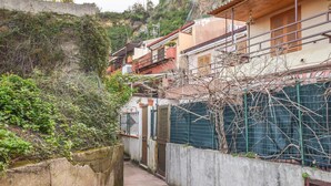 Un estrecho callejón con un muro de concreto a un lado y un edificio con balcón al otro.