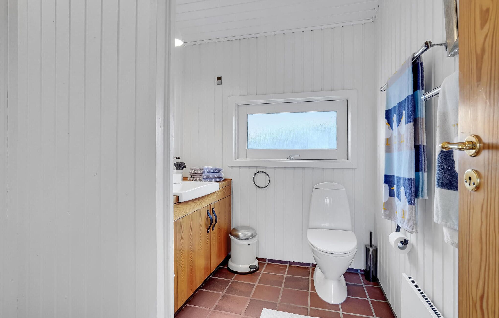 Un baño pequeño y funcional con inodoro, ventana, lavabo y cortina de ducha.