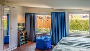 Ein Schlafzimmer mit Bett, Schreibtisch, Stuhl, Kleiderschrank und einem Fenster mit Vorhängen.