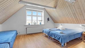 A bedroom with two beds, a window with a view, a radiator, and wooden ceiling beams.