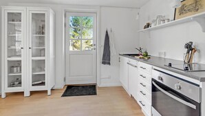 A kitchen with white cabinetry, a black doormat, a window with a view, and a stove.
