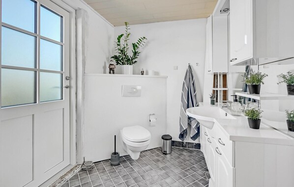 Ein kleines, modernes Badezimmer mit Toilette, Waschbecken und einem Fenster.