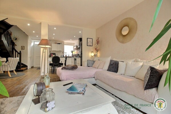 A modern living room with a sofa, a coffee table, and a lamp. There is a staircase leading to another room.