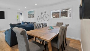 Ein modernes Wohnzimmer mit einem Holzesstisch, grau gepolsterten Stühlen, einem blauen Sofa und einem an der Wand befestigten Fahrrad.