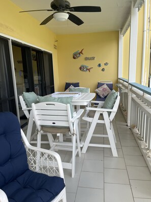 Ein Balkon mit Tisch und Stühlen, einem Deckenventilator und Wandbildern von Fischen.