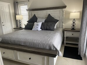Ein ordentlich eingerichtetes Schlafzimmer mit einem großen Bett, zwei Nachttischen und einem Beistelltisch.