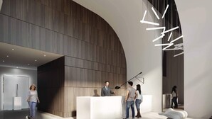 A modern reception area with a curved wooden wall, a white reception desk, and a contemporary light fixture.